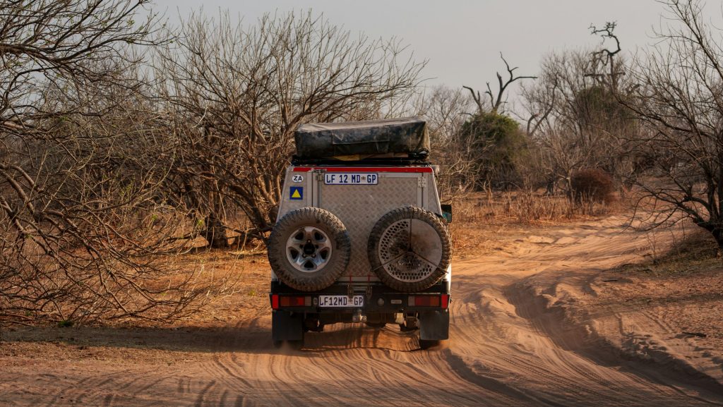 Overland 4x4 with rear-mounted spare wheels on a sandy bush track